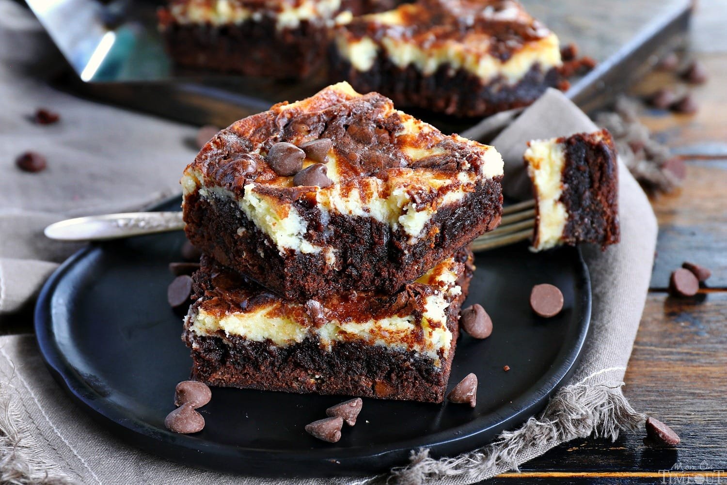 Cheese cake brownies lembut dan fudgy dengan lapisan cream cheese yang creamy, disajikan di atas piring putih.